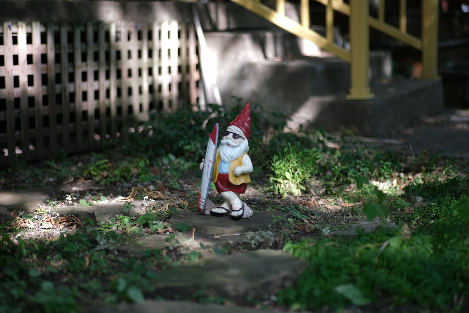A gnome with skis stands in a grassy yard.
